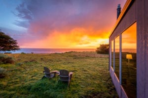 sunset at Sea Ranch Abalone Bay. Two Adirondack chairs in yard front of living room window 