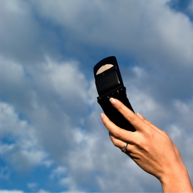 phone in woman's hand held up to sky with clouds