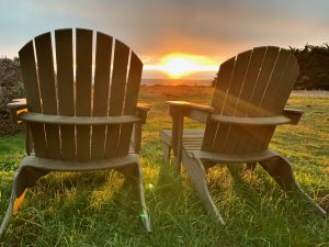 two adirondack chairs with the sunset between them