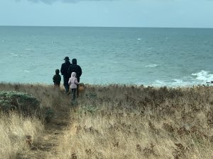 Father, mother, young boy and girl walk to the ocean bluff trail on cold winter day at Sea Ranch