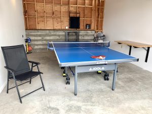 Ping pong table in garage with folding chairs, drop-down table, football, basketball, highchair
