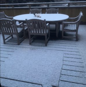 a dusting of snow covers picnic table, chairs and deck in The Sea Ranch