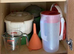 Plastic collapsible strainer is folded and stored next to a plastic pitcher