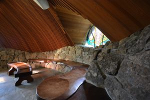 Interior benches of Sea Ranch Chapel shows rock wall and stain glass window
