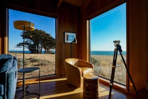 views from Sea Ranch Abalone Bay to the ocean. Brown leather swivel chair with telescope near by.Sea Ranch Abalone Bay- one of the best Airbnbs 